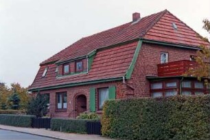 Lütjenseer Straße 8: traufständiges Backsteinhaus mit Mansarddach: Straßenfront mit eingezogenem Eingang, in Mansardgeschoss Schleppgaube: rechts Giebelseite mit Altan auf Wintergarten: Vorgartenhecken, Gartenpforte