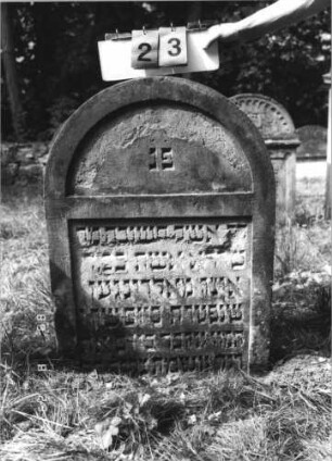 Grabstein 23 (Index: 100110914) Material: Sandstein Zustand: stark verwittert mit geringem Textverlust Maße HxBxT: 109x73x11 cm Beschreibung: Stele, Rundbogenabschluß, Schriftfelder eingetieft: Grabstein 23