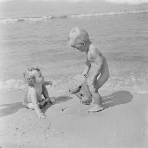Zwei nackte Kleinkinder spielen am Strand