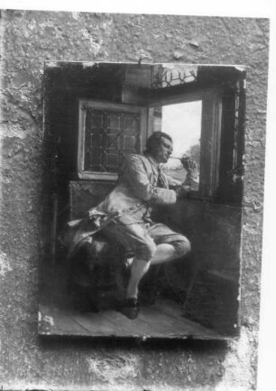 Sitzender junger Mann, aus einem geöffneten Fenster schauend
