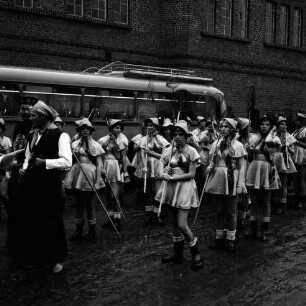 Karpfenfest: Umzug: Fischerinnengarde mit Keschern: links "Länder-Kostüm" Chinese: dahinter Reisebus, Ziegelfassade, 8. Oktober 1961