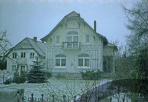 Reinbeker Straße 10: giebelständiges Wohnhaus: Straßenfront mit Gesims, Balkon, hölzerner Giebelzier: rechts an Traufseite vorgebauter Windfang mit Eingangstür: hinten links Wohnhaus