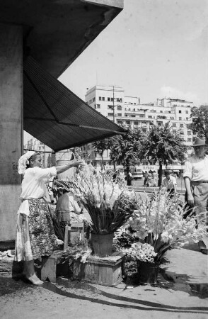 Bukarest, Boulevard Nicolae Bălcescu. Blumenstand mit Verkäuferin vor einem Laden