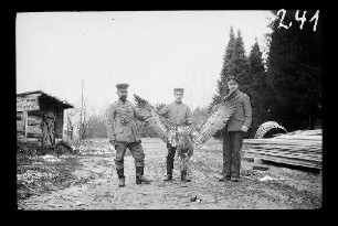 bei Bialowiesk (?) (=Bia³owie¿a, Polen): 2 Offiziere mit Schirmmütze, 1 Soldat mit Feldmütze mit einem an den Flügeln auseinandergehaltenen "erlegten Seeadler"