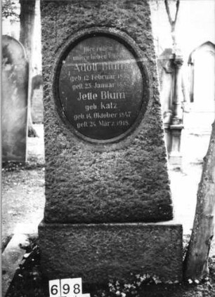 Grabstein 698 (Index: 99630200) Material: Granit mit geschliffener Platte Zustand: gut Maße HxBxT: 160x74x45 cm Beschreibung: Stele auf Sockel mit ovaler Schriftplatte: Grabstein 698