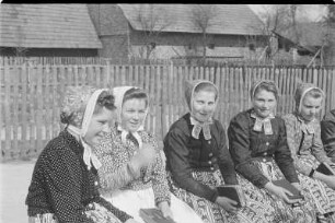 Mädchen in Schleifer Tracht aus Rohne auf der Singebank in Rohne. : Holcy w Slepjanskej drasće z Rowneho na spěwarskej ławcy w Rownom.