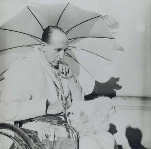 Marquis George de Cuevas im Rollstuhl unter einem Sonnenschirm