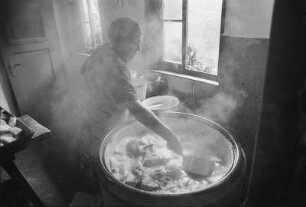 Die Bäuerin am Kessel kocht Fleisch aus