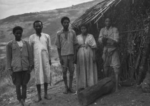 Amhara-Gruppe : Eine Gruppe der Amhara vor einer Strohhütte, einer von ihnen ein Soldat mit Gewehr in der Hand.