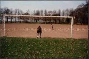 Auf einem Fußballsandplatz, Junge schießt auf ein Tor mit Torwart (Prämiertes Foto G)