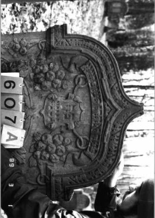 Grabstein 607 (Index: 99753121) Material: Sandstein Zustand: gut, Stele eingesunken Maße HxBxT: 138x78x13 cm Beschreibung: Stele, eingezog. Kielbogenabschluß, ovales Schriftfeld Symbolik: Wappenschild, Feigen, Trauben, Lorberkranz, Blätter, Schriftband: Grabstein 607A