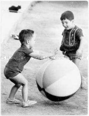 Zwei kleine Jungen spielen mit einem großen Ball