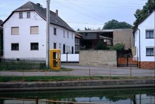 Blick über den Dorfteich auf einen Hof; Telefonzelle