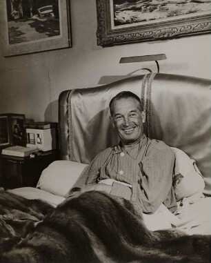 Maurice Chevalier im Bett sitzend