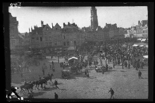 Cambrai (Dep. Nord, Frankreich): Marktplatz mit einer Menschenmenge bei den Marktständen und durchreitenden Soldaten, im Hintergrund der Glockenturm [=Belfried] (Blick von schräg oben)