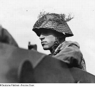 Soldat mit Stahlhelm (mit Tarnnetz und Zweigen)