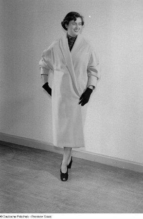 Eine Frau posiert mit Mantel und Handschuhen bei der "Internationalen Messemodenschau", Herbstmesse 1953