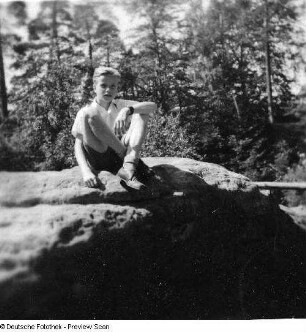 Junge auf einem Felsen sitzend
