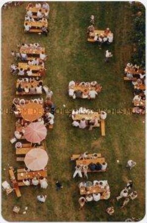 Von oben fotografierte Menschen beim Kaffeetrinken im Garten (Altersgruppe bis 14)