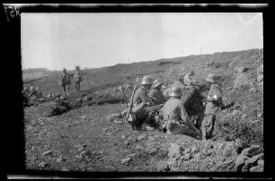 Übungsgelände I bei Mouzon (Dep. Ardennes, Frankreich): 4 Soldaten mit Stahlhelm bei einer Pause am Rand eines Grabens (Rückansicht, Distanzaufnahme) ("im Graben")