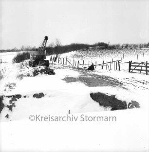 Steensrade: Gemeindeweg in Richtung Meddewade: Bauarbeiten an Durchbruch: hinten links Bagger: hinten rechts eingezäunte Wiesen: Winter