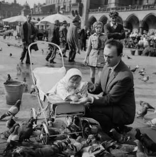 Krakow. Hauptmarkt mit Tuchhallen, Passanten beim Taubenfüttern