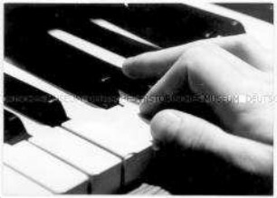 Hand auf Klaviertasten (Altersgruppe bis 14)