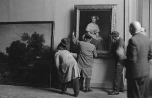 Eröffnung der Dauerausstellung in der Alten Nationalgalerie : Ludwig Justi, Direktor der Nationalgalerie, mit Aufbauhelfern beim Aufhängen des Gemäldes "Bildnis der Sängerin Jenny Lind" von Eduard Magnus