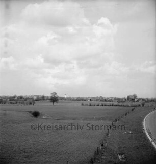 Blick von der Brücke der B 404 über die Landstraße zwischen Mollhagen und Todendorf auf Mollhagen: vorn Weiden: im Hintergrund Häuser und Silo der Spar- und Darlehnskasse Mollhagen eGmbH