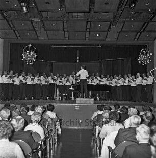 Städtischer Musikkreis Bad Oldesloe e.V.: 35-jähriges Jubiläum: Festhalle der Dietrich-Buxtehude-Schule [früher Königin-Luise-Schule, Realschule], Grabauer Straße: Jubiläumskonzert: auf Bühne: Oldesloer Männerchor von 1844 singt unter Leitung von Wilhelm Albeck: Blumenschmuck: vorne Publikum auf Stuhlreihen, 19. September 1981