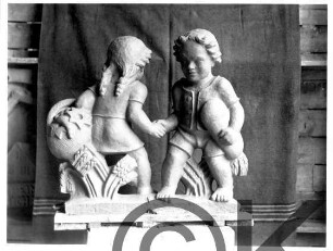 Nasenschild Bäckerei H. Schriefer: Knabe und Mädchen bei Händedruck, mit Korb, Brot, Getreidegarben: Entstehungsprozess: Tonmodell in Atelier, hinten Vorhang;