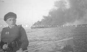 Selbstversenkung des Hochseepassagierdampfers "Columbus" am 19. Dezember 1939, im Vordergrund ein junger Matrose mit Schwimmweste im Rettungsboot