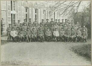 44 Offiziere in Uniform mit Mütze oder Pickelhaube des Oberkommandos der 7. Armee teils stehend, teils sitzend vor Fensterfront eines Gebäudes in einem Park