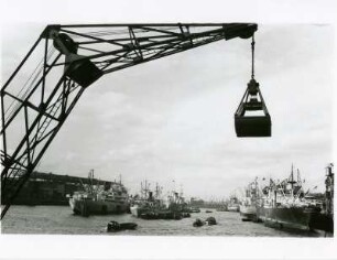 Hamburg. Hafen. Betriebsamkeit. Frachtschiffe werden entladen. im Vordergrund ein Kran mit einem Greifer zur Entladung von Schüttgut