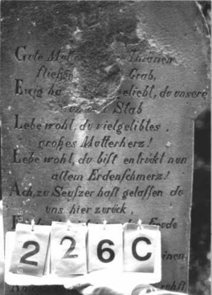 Grabstein 226 (Index: 100107001) Material: Sandstein Zustand: verwittert, Mittelaufsatz fehlt Maße HxBxT: 129x63x20 cm Beschreibung: Ädikulaartige Stele mit Rundbogenabschluß, Mittelaufsatz fehlt, Halbsäulen, Schriftfeld rechteckig eingetieft, Sockel Symbolik: floral: Grabstein 226C