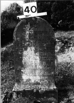 Grabstein 40 (Index: 99801988) Material: Sandstein Zustand: verwittert mit Textverlust Maße HxBxT: 77x32x16 cm Beschreibung: Stele, Sockel, Rundbogenabschluß Besonderheit: Kindergrab: Grabstein 40
