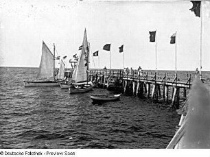 Seebrücke mit Flaggen und Segelbooten in der Ostsee
