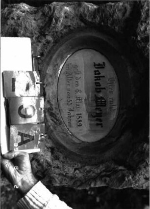 Grabstein 29 (Index: 100101434) Material: Kalkstein, weiße Marmorplatte Zustand: gut Maße HxBxT: 135x57x28 cm Beschreibung: grob stelenhaft behauener Stein, ovale Schriftplatte: Grabstein 29A