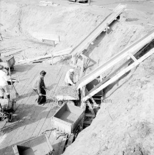 Erweiterungsbau [später Gebäude C] mit Kreistagssitzungssaal: IV. Bauabschnitt: Baugrube an der Reimer-Hansen-Straße: Erstellen der Fundamente für den Kreistagssitzungssaal: rechts Rutsche für Frischbeton, davor Transportkarren: links Bauarbeiter