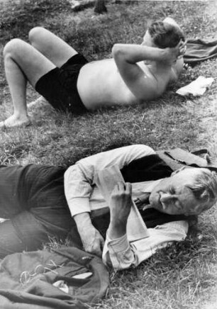 Männer liegen während einer Pause im Gras am Strand der Elbe bei Nienstedten. Einer liest eine Zeitung