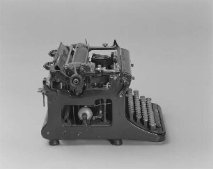 Typenhebelschreibmaschine "Ideal" (Modell C). Vorderanschlag (sofort sichtbare Schrift), Farbband. Seitenansicht von links oben