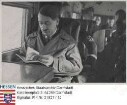Hitler, Adolf (1889-1945) / Sammelwerk Nr. 15 'Adolf Hitler', Bild Nr. 12, Gruppe 64 / Porträt Adolf Hitlers, im Flugzeug sitzend und in einem Buch blätternd, Brustbild