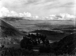 Becken von Cochabamba : Im Vordergrund Vegetation und ein Gebäude, im Hintergrund mit Wolken umschlossene Gipfel.