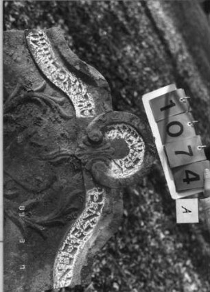 Grabstein 1074 (Index: 99753327) Material: Sandstein Zustand: leicht verwitt/Stele nach hinten gekippt Maße HxBxT: 142x78x13 cm Beschreibung: Stele, geschwungen eingezog. Rundbogenabschl. , ovales Schriftfeld Symbolik: Ranken, Herz: Grabstein 1074A