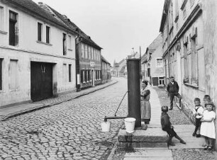 Mühlberg (Elbe). Blick in eine Straße mit Wohnhäusern und Trinkwasserbrunnen