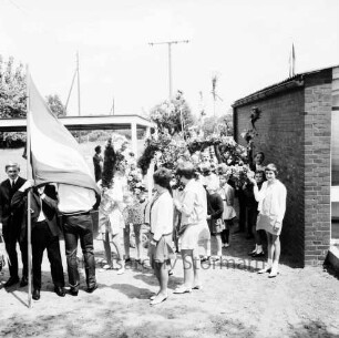 Tralau: Kindervogelschießen: Dörfergemeinschaftsschule: Schulhof: Aufstellung der Schulkinder zum Festumzug mit Blumenbögen: links Fahne und Pkw-Heck: rechts Schulgebäude: hinten links Fahrrad- und Pkw-Unterstand