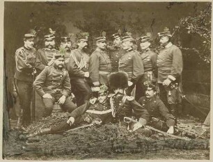 Stabsquartier des Süd-Corps im Manöver 1869, dreizehn Offiziere teils stehend, sitzend, teils liegend, in Uniform, Mütze, teils mit Orden