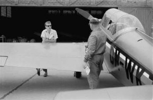 Riesa. Fluglehrer Wolfgang Winkler steht neben einem Motorflugzeug und unterhält sich mit einem anderen Mann