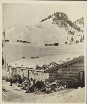 Deutschland. Oberbayern. Skifahrer rasten vor einer Hütte auf der Schönfeldalm bei Schliersee. Im Hinergrund der Rotwandkopf