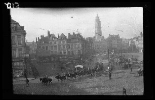 Cambrai (Dep. Nord, Frankreich): Marktplatz mit einer Menschenmenge bei den Marktständen und durchreitenden Soldaten, im Hintergrund der Glockenturm [=Belfried] (Blick von schräg oben)